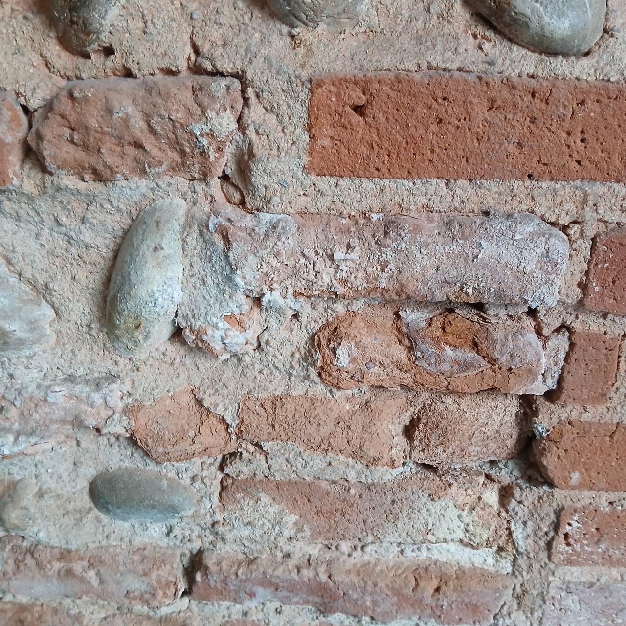Détail briques foraine et galets ronds — surface poussiéreuse, joints effrités